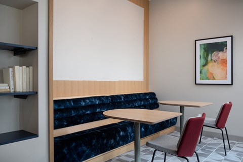 A room with a blue couch, a table and two chairs.