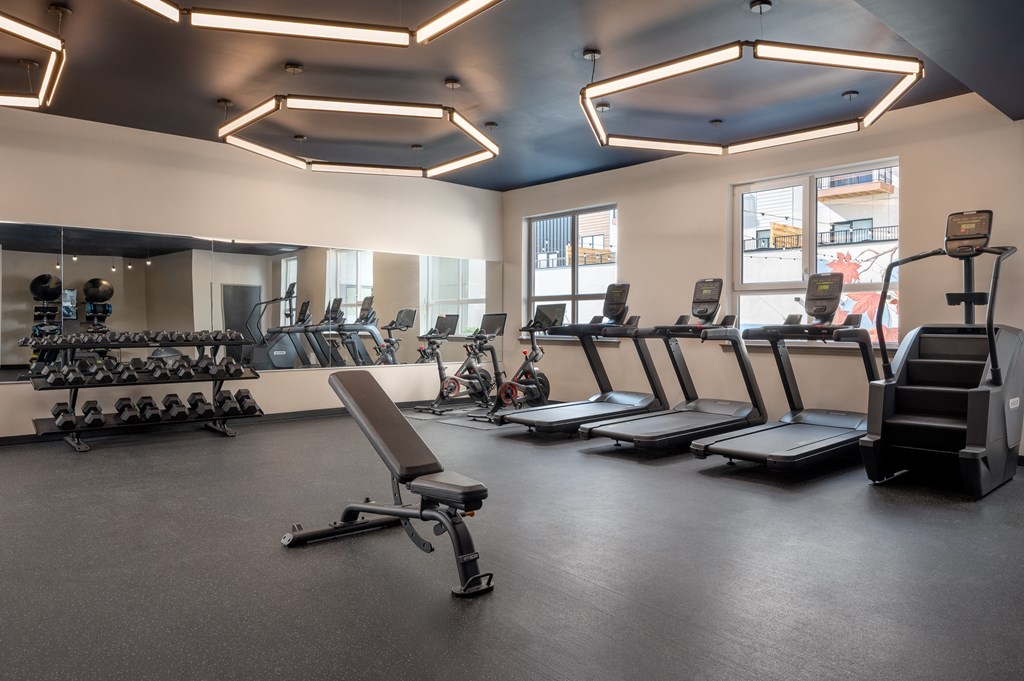 A gym with treadmills, exercise bikes, and weights.