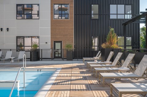 A pool with sun loungers in front of a building.