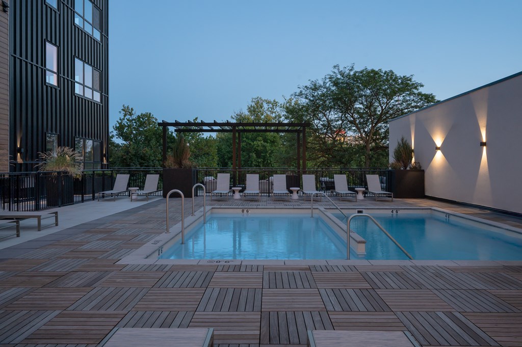A pool surrounded by wooden decking and lounge chairs.