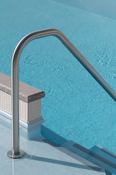 A silver pool ladder leads into a blue swimming pool.