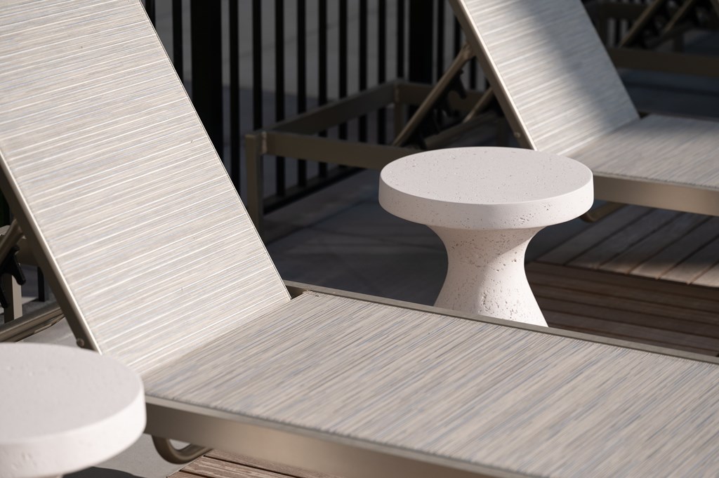 A white chair with a round back is placed on a wooden deck.