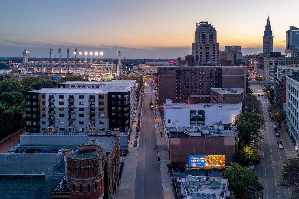 A cityscape with buildings and a baseball field at dusk.