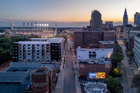 A cityscape with buildings and a baseball field at dusk.