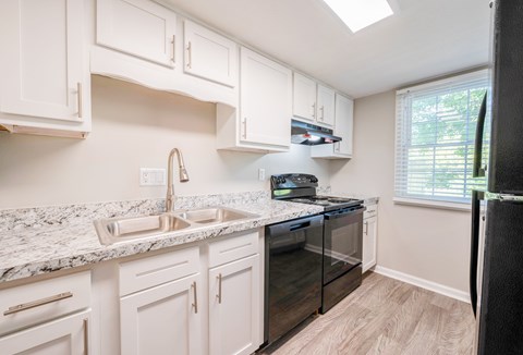 A kitchen with white cabinets and a marble countertop.