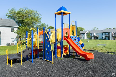 A playground with a blue and yellow structure and a red slide.