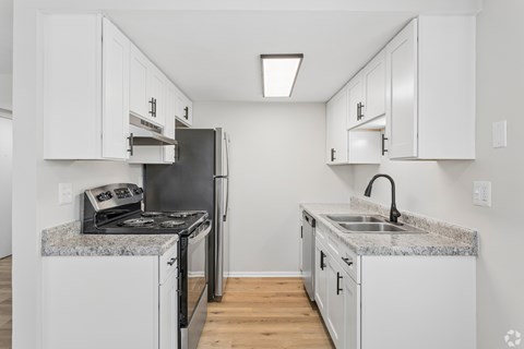A kitchen with white cabinets and granite countertops.