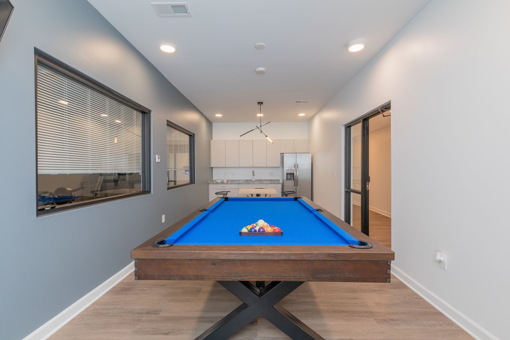 A pool table in a room with a window and a door. at The Lumos Apartments, Cleveland, Ohio