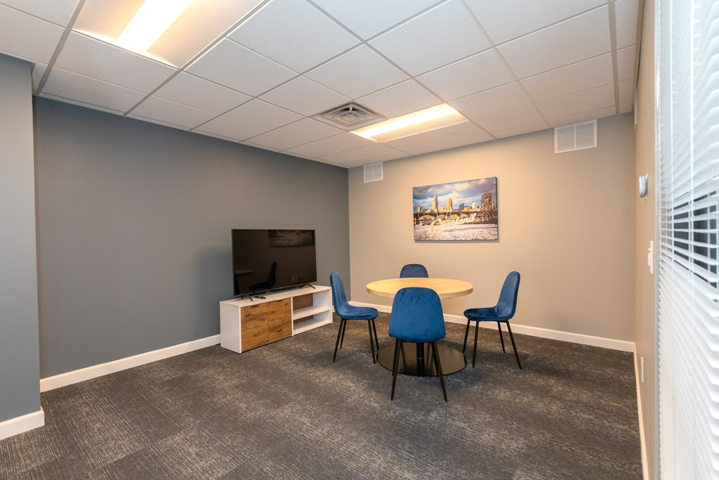 A conference room with a table, chairs, and a television. at The Lumos Apartments, Cleveland, OH, 44106