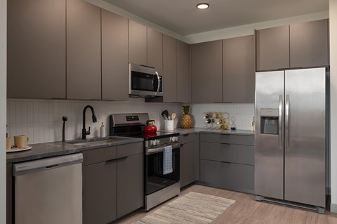 A modern kitchen with a stainless steel refrigerator and a microwave above the stove.