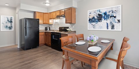 A modern kitchen with a wooden table set for two.
