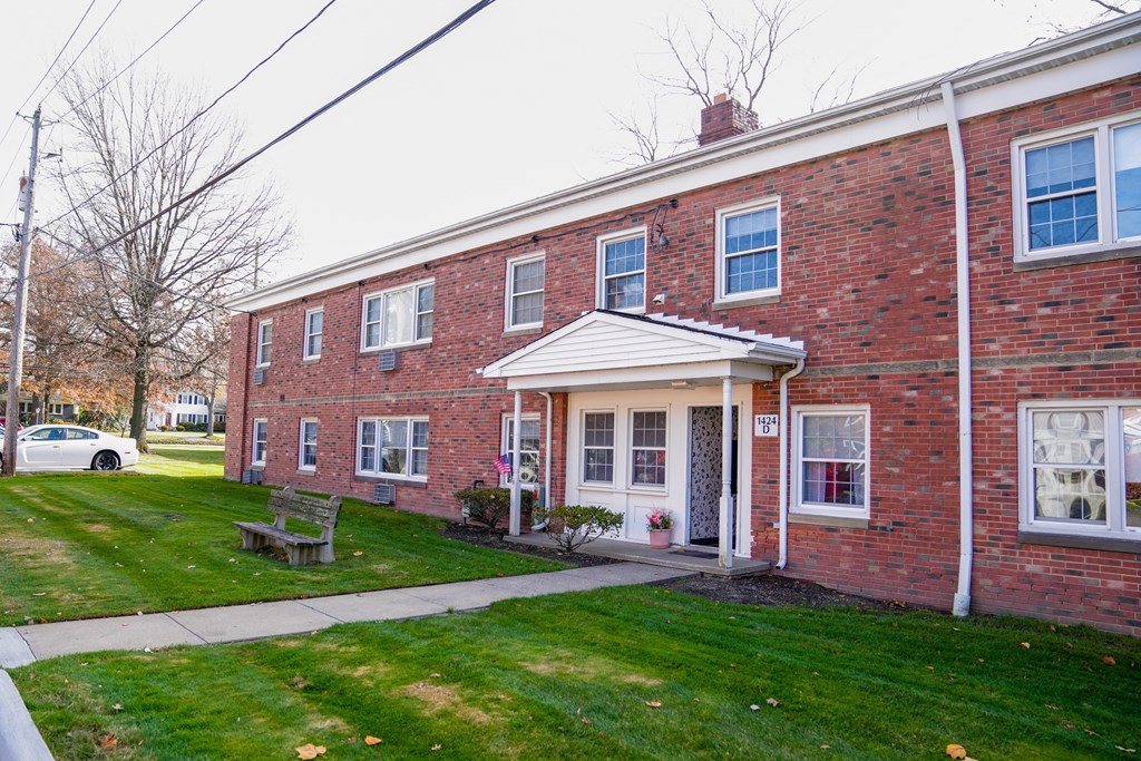the front of a brick building with a sidewalk and grass