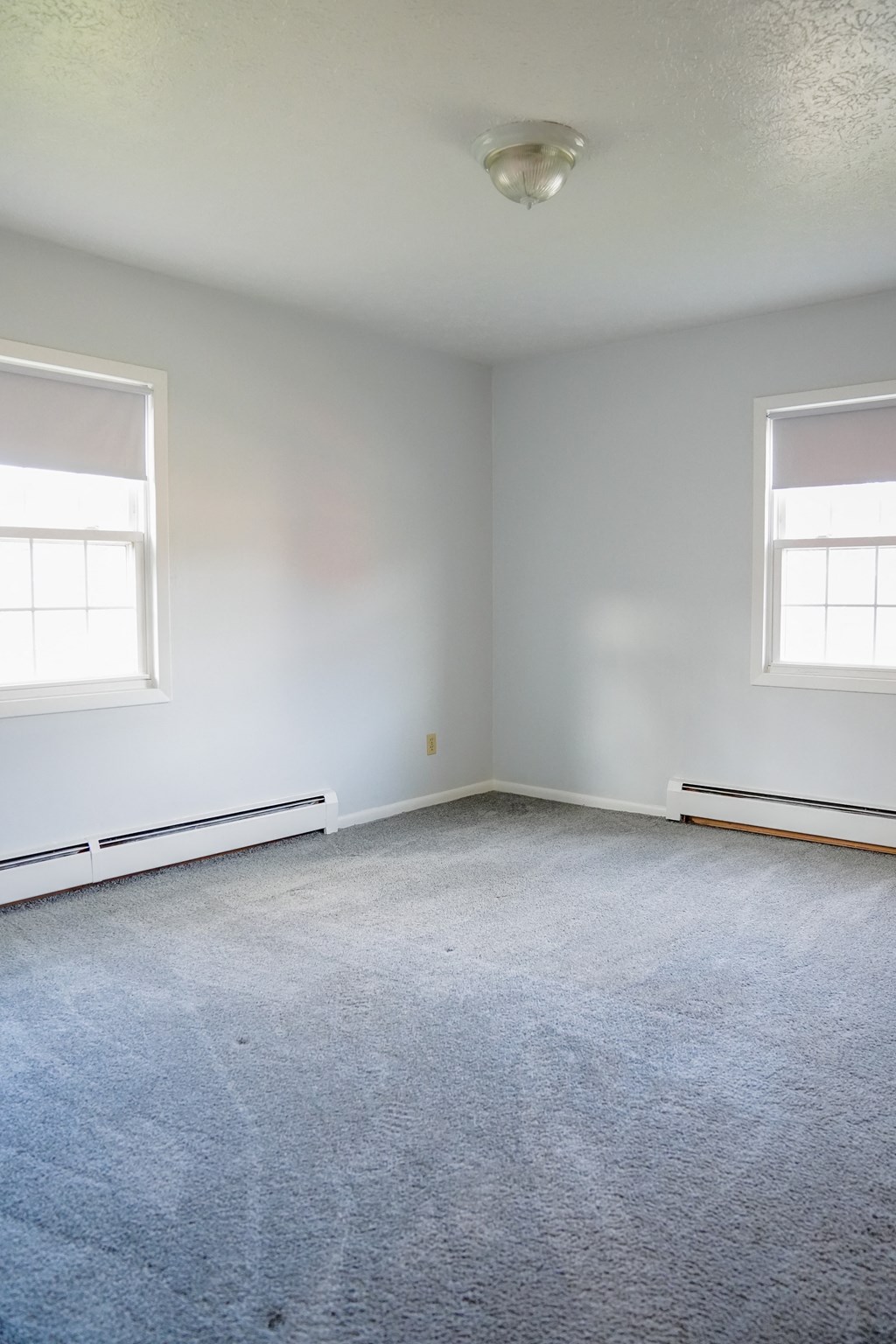 an empty room with two windows and a ceiling fan