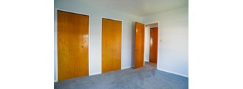 three doors in a room with carpet and white walls