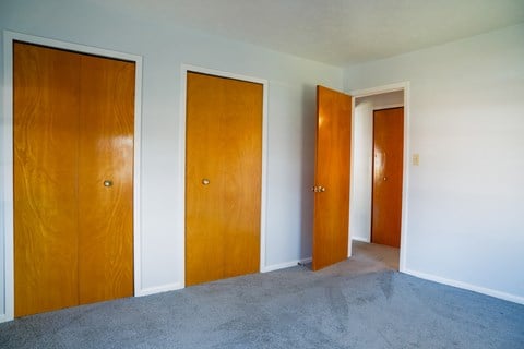 three doors in a room with carpet and white walls