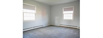 an empty room with two windows and a carpet