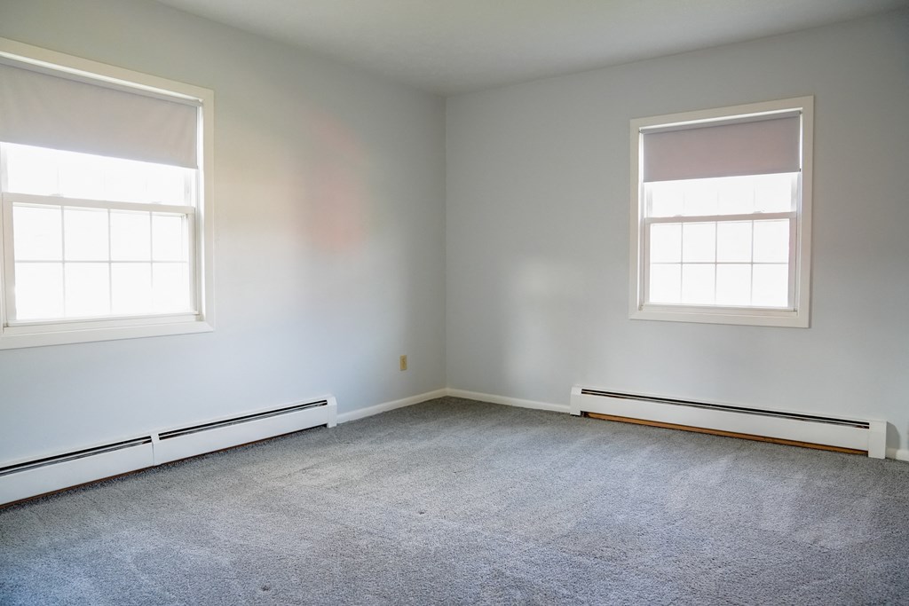 an empty room with two windows and a carpet