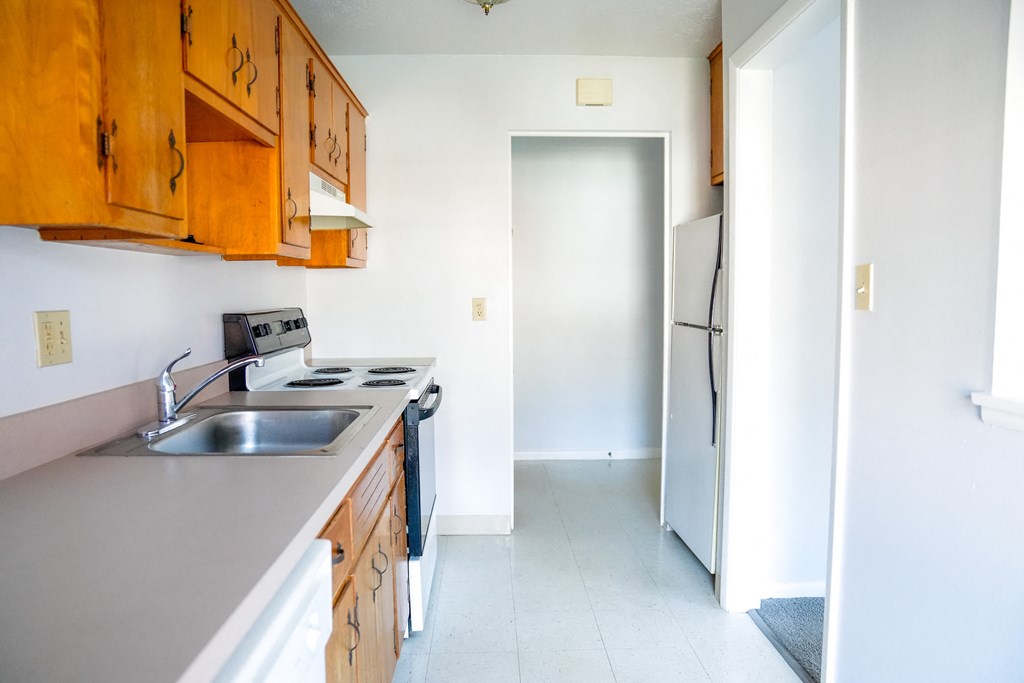 an empty kitchen with a sink and a refrigerator
