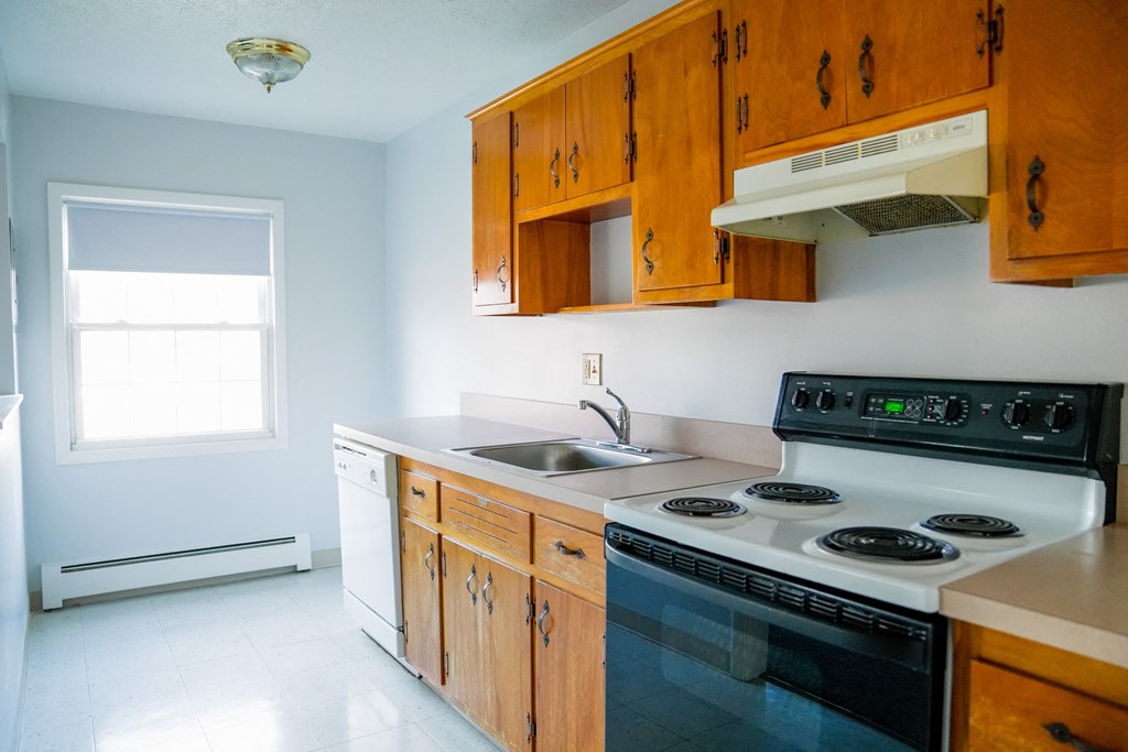 a kitchen with a stove and a sink and wooden cabinets