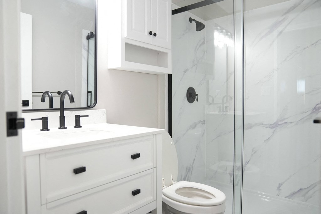 an updated white bathroom with a shower sink and toilet