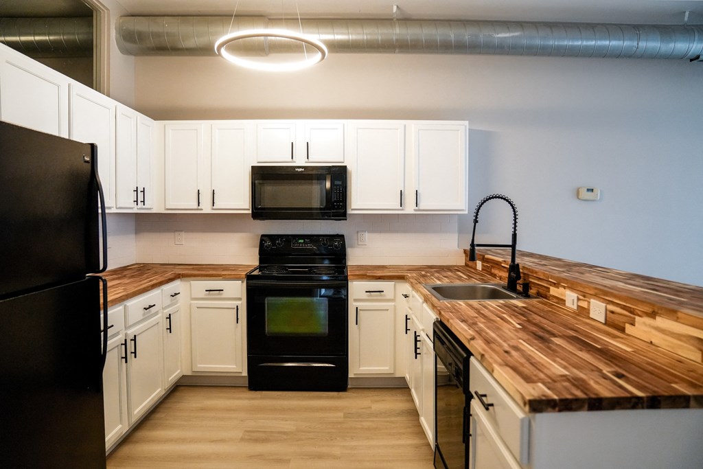 a kitchen with white cabinets and black appliances