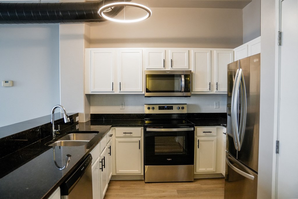 a kitchen with black countertops and white cabinets and stainless steel appliances