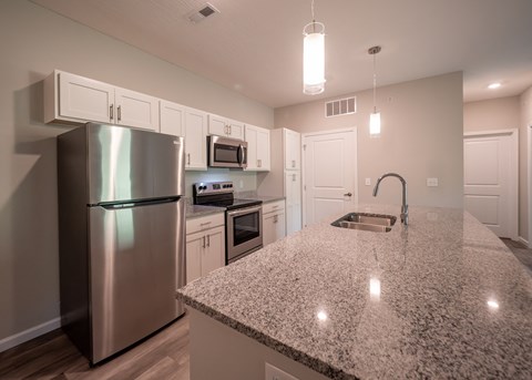 a kitchen with a granite counter top and stainless steel refrigerator