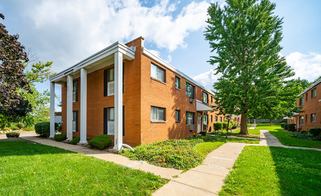 a brick apartment building with a sidewalk and trees