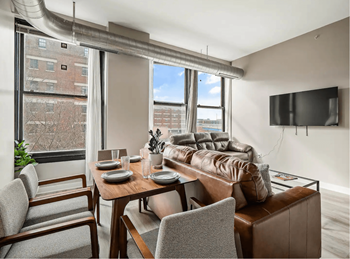 a living room with a leather couch and a table and chairs