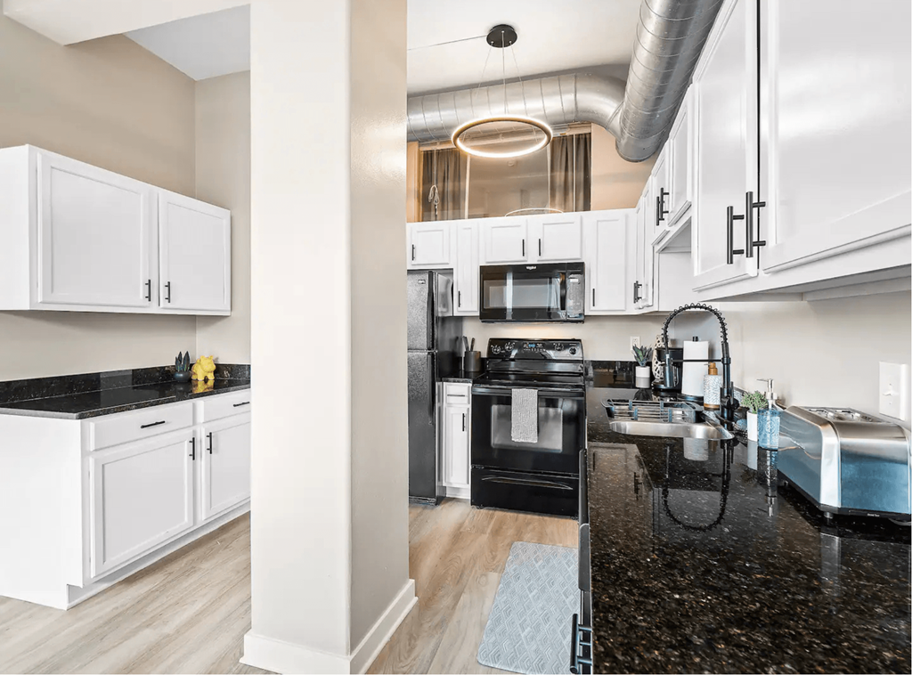 a kitchen with white cabinets and black counter tops
