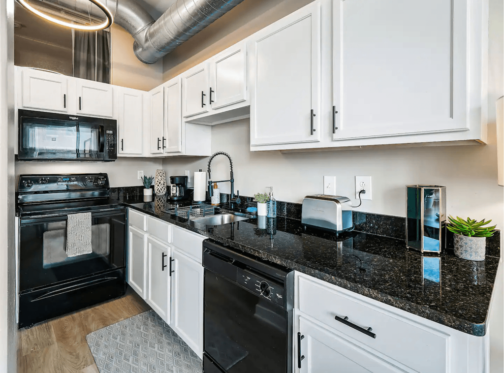 a kitchen with black counter tops and white cabinets
