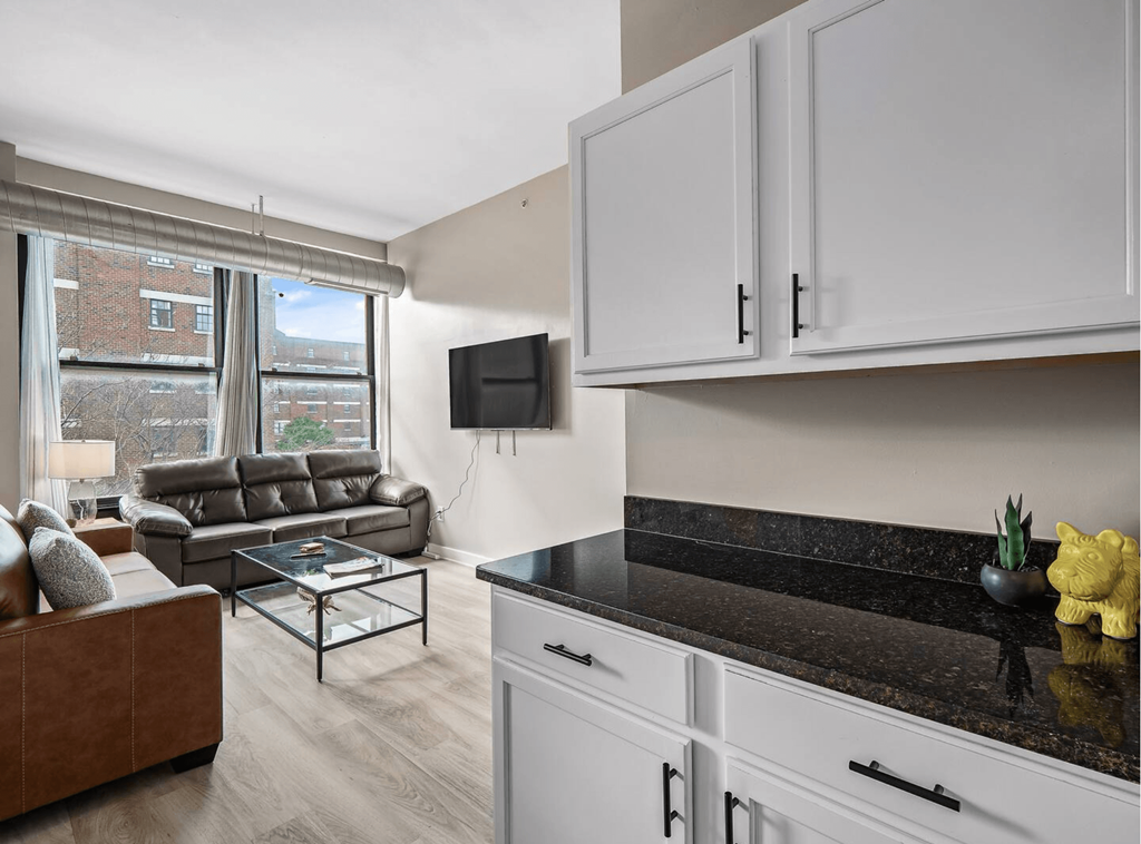 a kitchen with white cabinets and a living room with a couch and a tv