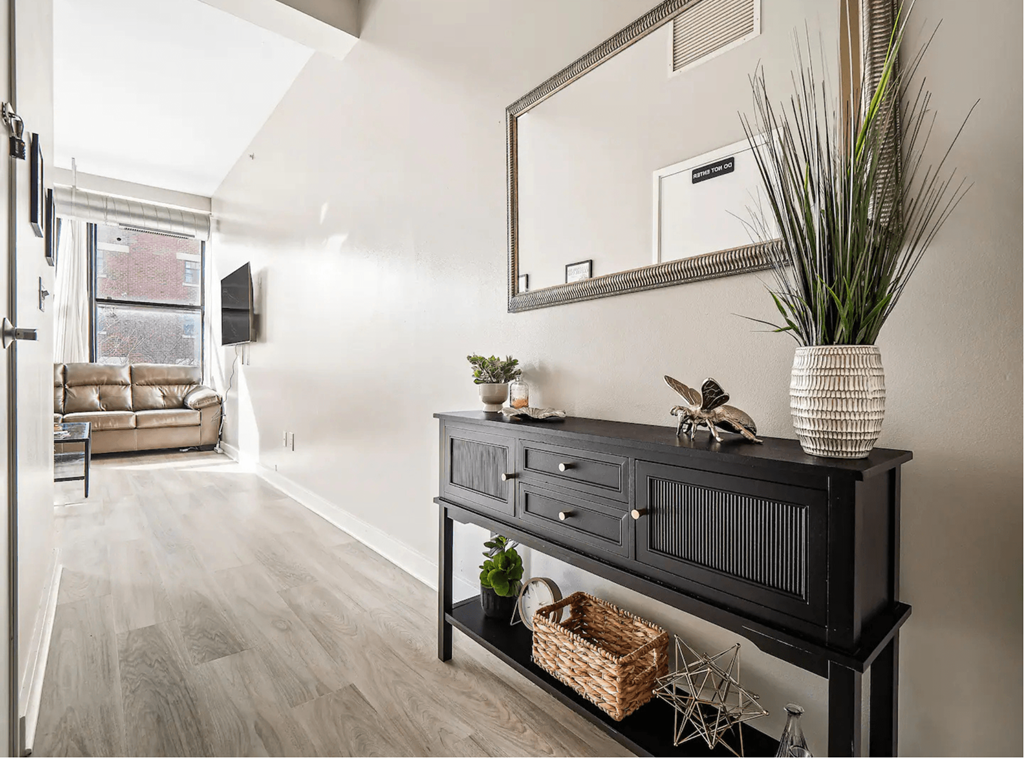 a living room with a black dresser and a mirror