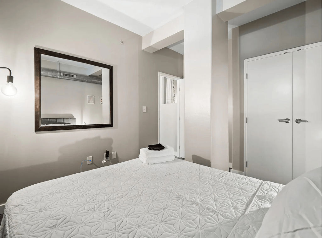 a bedroom with a large bed and a mirror