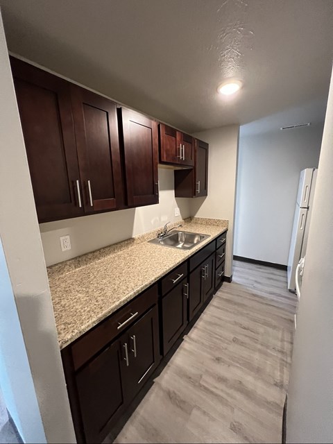 A kitchen with brown cabinets and a granite countertop.