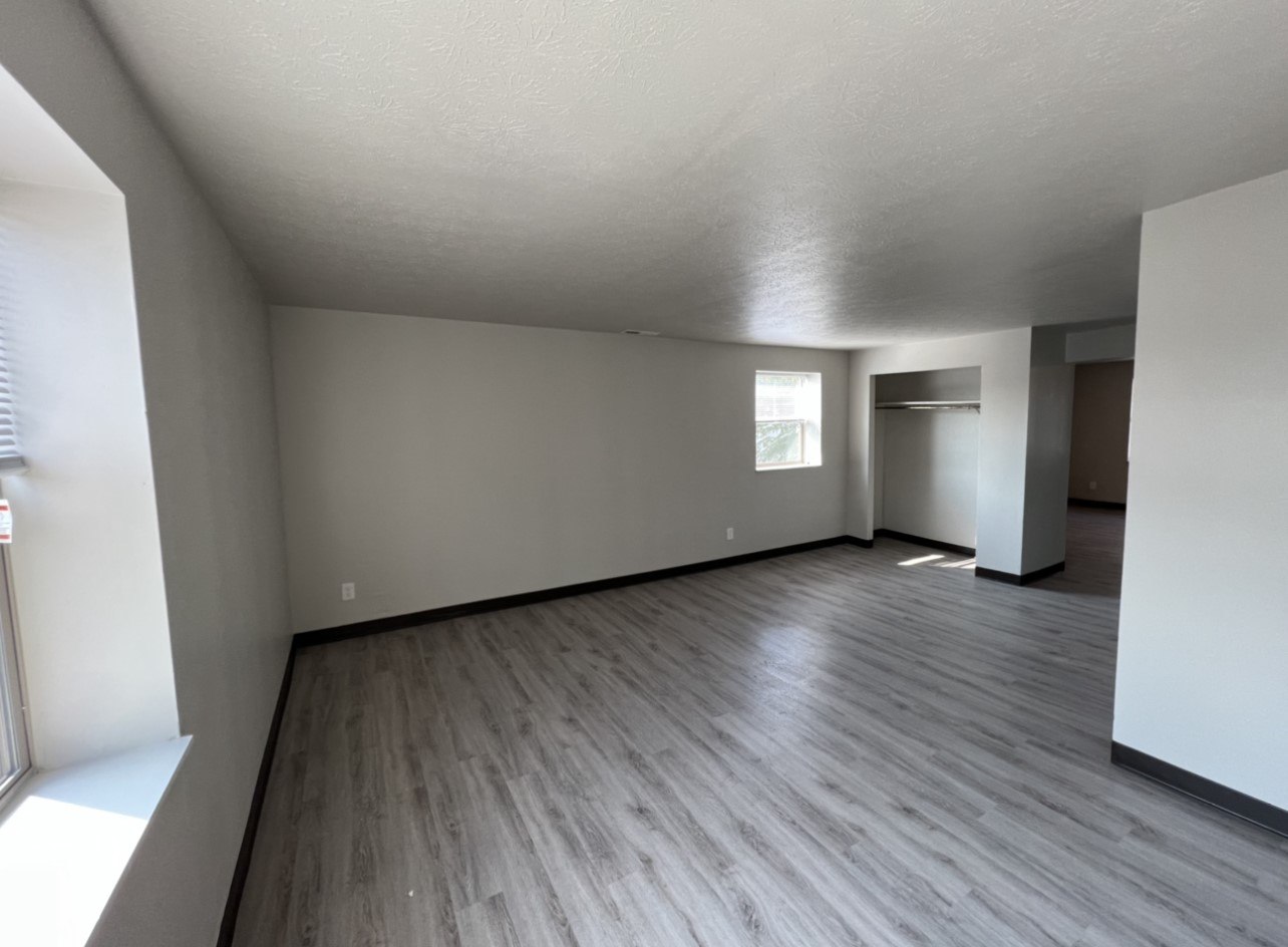 A room with wooden flooring and white walls.