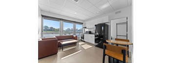 A modern kitchen with a brown couch and a wooden table.