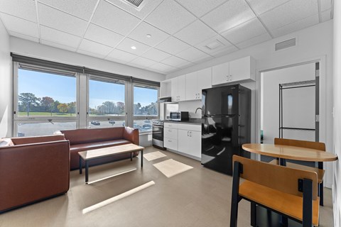 A modern kitchen with a brown couch and a wooden table.
