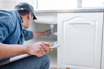 a man plumbing a bathroom sink with a pair of scissors