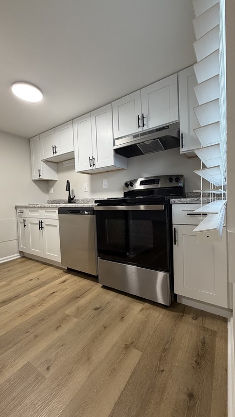 A kitchen with stainless steel appliances and white cabinets.