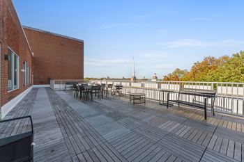 A wooden deck with benches and a table is surrounded by a metal fence.
