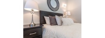 a bedroom with a bed and a nightstand with two lamps