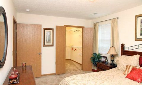 A bedroom with a bed, nightstand, and a mirror.