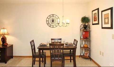 A dining room with a table set for two and a clock on the wall.