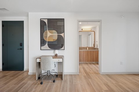 A room with a desk and a painting on the wall.