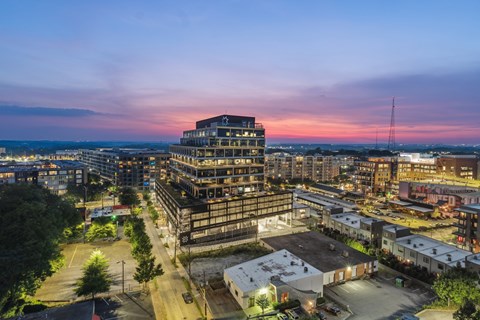 A cityscape at dusk with a large building under construction in the foreground.
