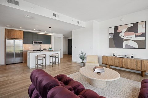 A modern living room with a kitchen in the background.