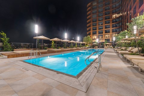 A large outdoor swimming pool surrounded by lounge chairs and umbrellas.