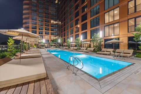 A large outdoor swimming pool surrounded by lounge chairs and umbrellas.