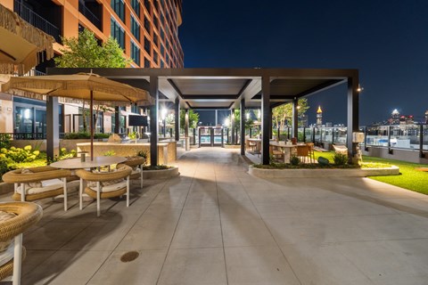 A patio area with tables and chairs is lit up at night.
